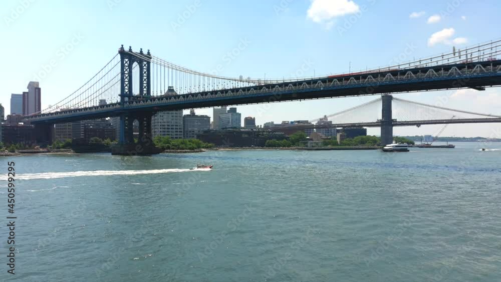 Aerial Pan View of a Speedboat Going Under the Brooklyn and Manhattan Bridge Aerial Pan View of a Speedboat Going Under the Brooklyn and Manhattan Bridge