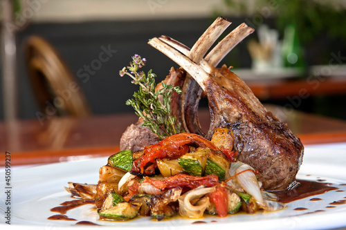 фотографія Roasted rack of lamb or rack of veal accompanied with vegetables and sauce, serv