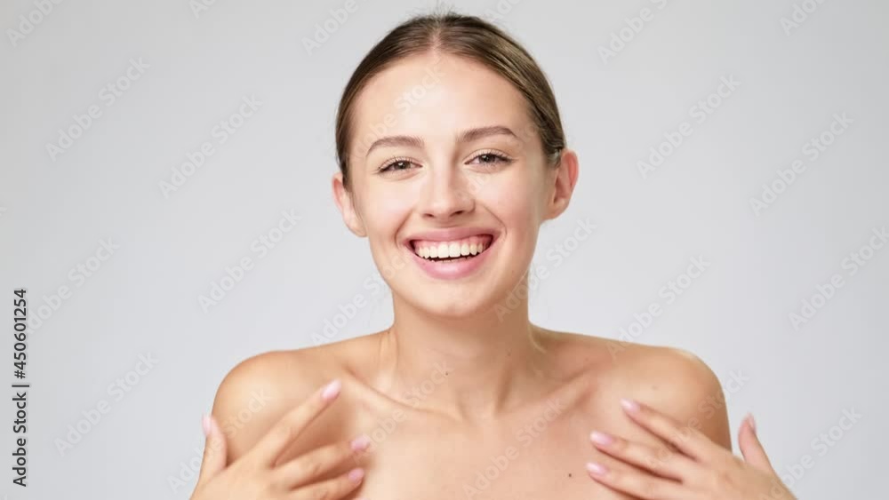 Beautiful Young Woman with Clean Fresh Skin standing over light grey background Beautiful Young Woman with Clean Fresh Skin standing over light grey background