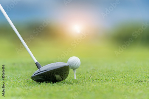 Close up golf club and golf ball ,professional golfer teeing golf ball to hole at golf course to win in game ,green grass and sunlight rays background