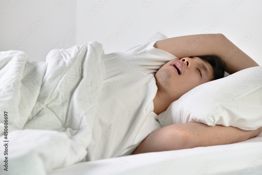 Young Asian man sleeping and snoring loudly lying in the bed. Young Asian man sleeping and snoring loudly lying in the bed.