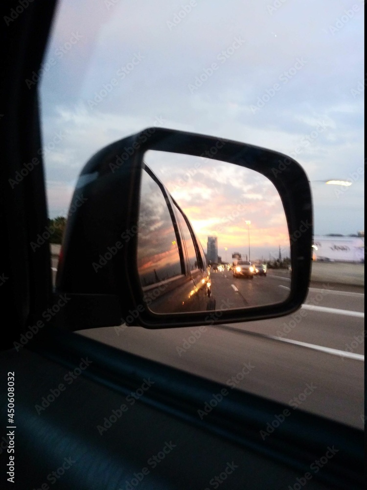 Sunset in the rearview mirror on the highway