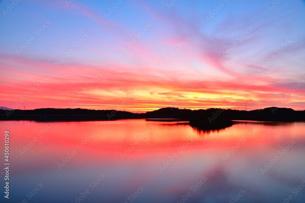水面に反射する夕焼けの空、夏の湖の夕景