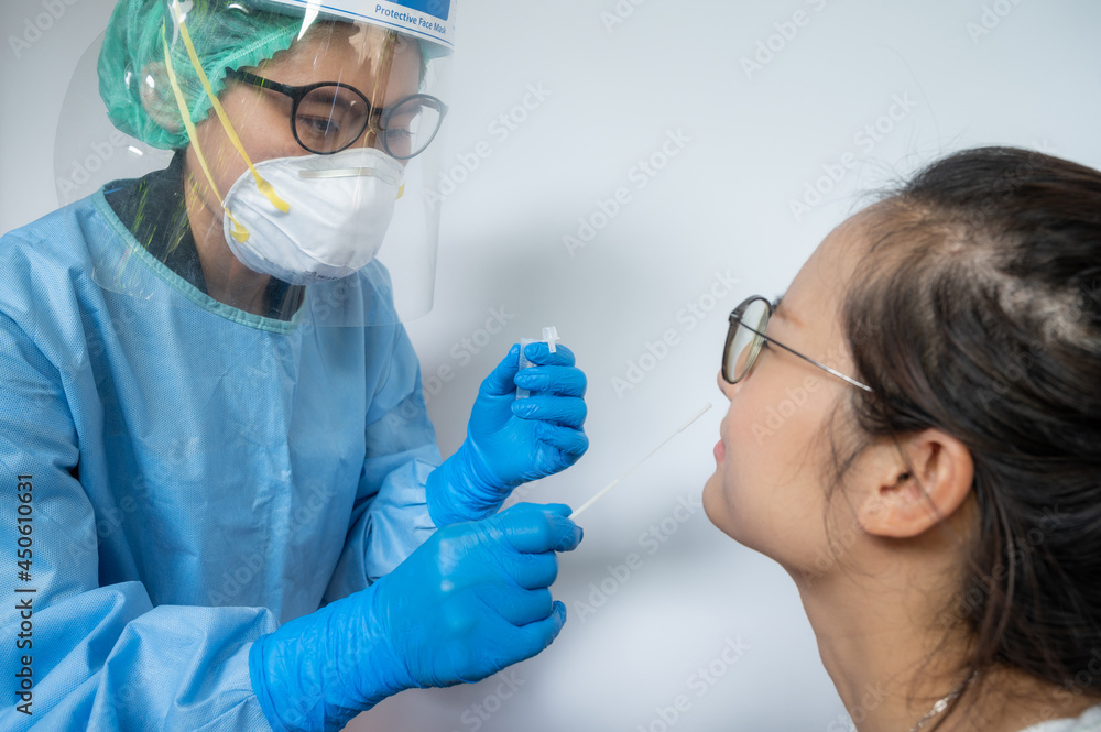 Healthcare worker trying to taking a nasal swab from Asian woman for testing diagnosis of covid-19 infection. Healthcare worker trying to taking a nasal swab from Asian woman for testing diagnosis of covid-19 infection.