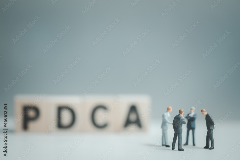 A group of businessmen meeting and standing in front of blur of PDCA letters by wooden block word. A group of businessmen meeting and standing in front of blur of PDCA letters by wooden block word.