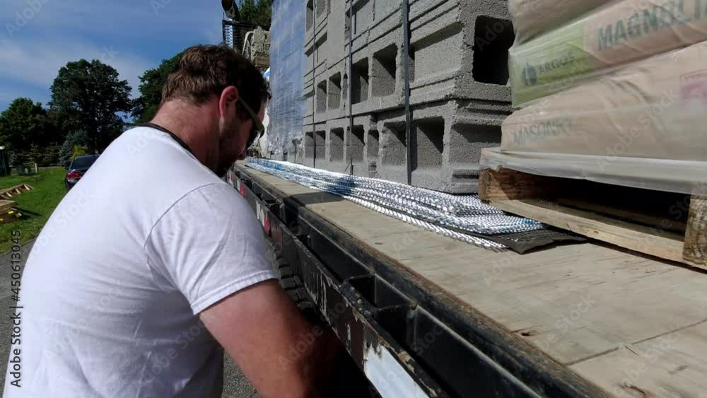 Trucker secures load on load of masonry supplies Trucker secures load on load of masonry supplies