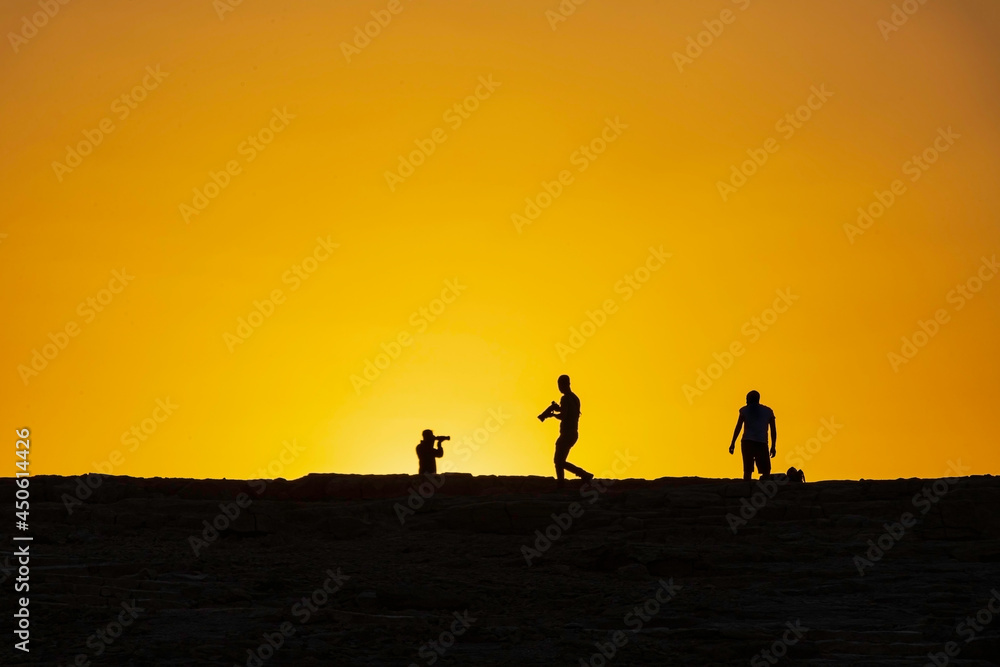 Silhouettes of photographers against the background of the rising sun. Makhtesh Ramon