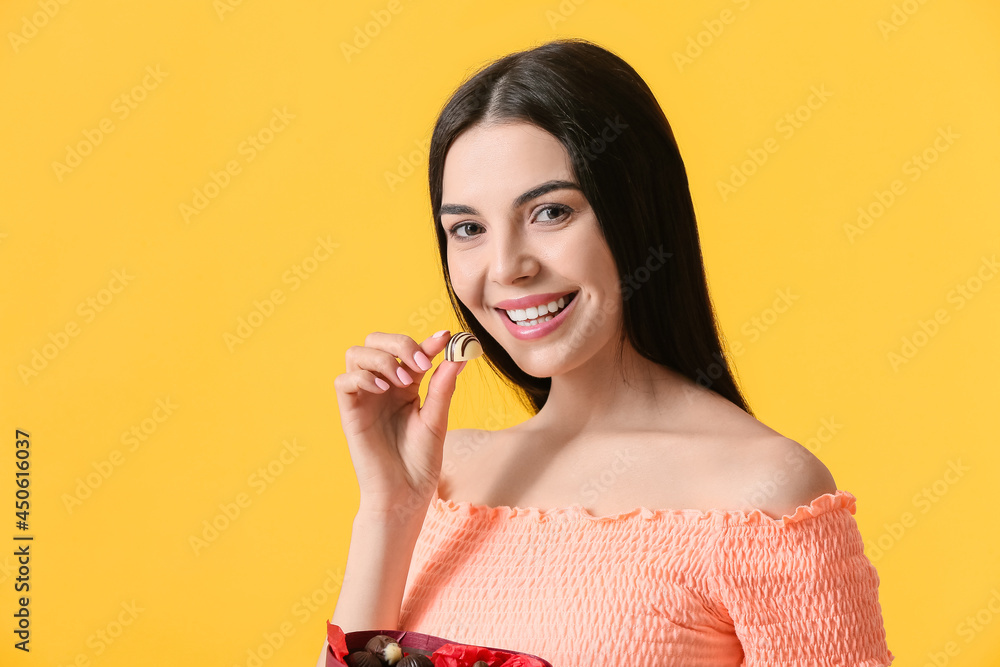 Beautiful young woman with chocolate candies on color background Beautiful young woman with chocolate candies on color background