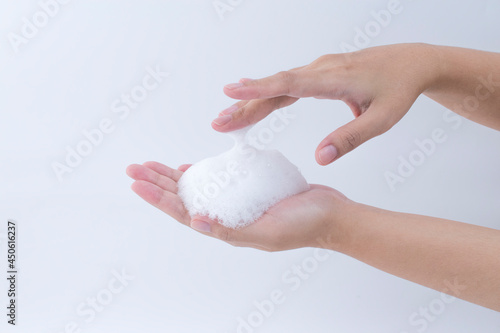 white soapy foam bubbles texture on hand. cleaning and wash essence facial cleanser skin care concept