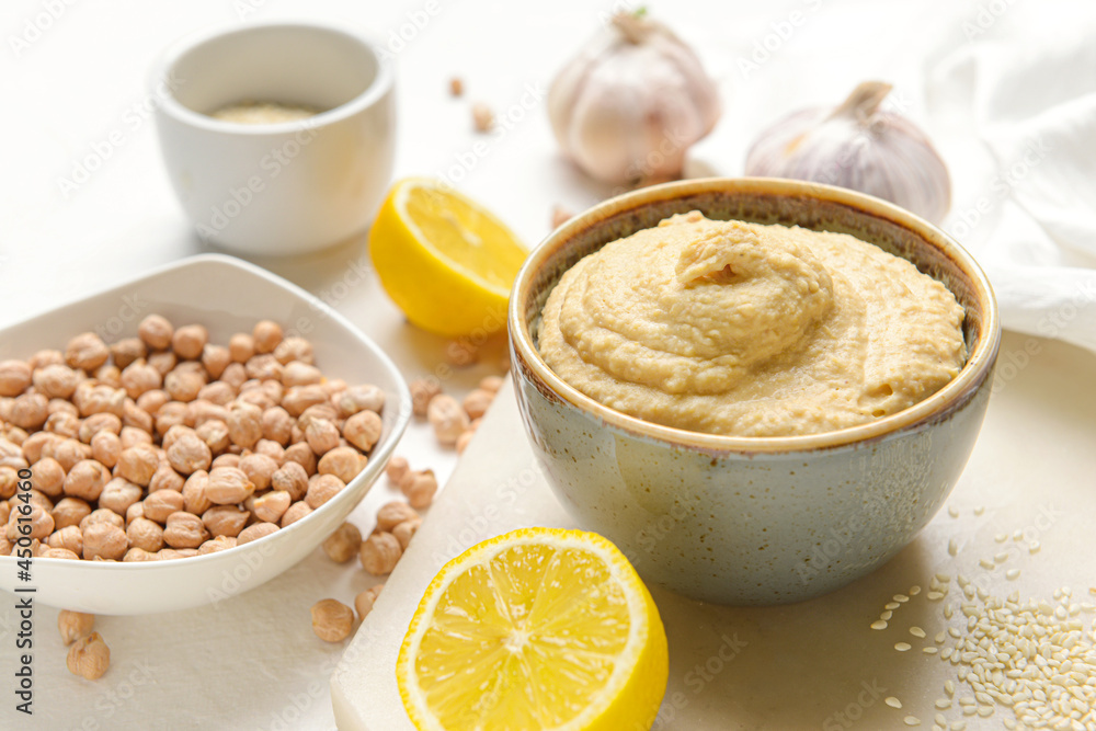 Bowl with tasty hummus and ingredients on table Bowl with tasty hummus and ingredients on table