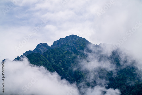 Fototapeta Naklejka Na Ścianę i Meble -  富山県中新川郡上市町の中山から立山の剱岳を望む登山をしている風景 A view of mountain climbing with a view of Tsurugidake in Tateyama from Nakayama in Kamiichi Town, Nakashinagawa County, Toyama Prefecture.