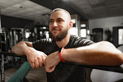 Cheerful smiling man bodybuilder standing in a gym