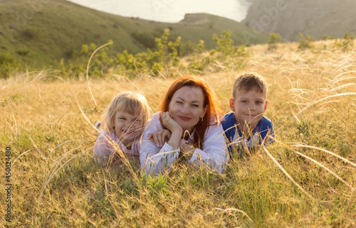 Happy family- mother, son and dauther poising on the meadow close up
