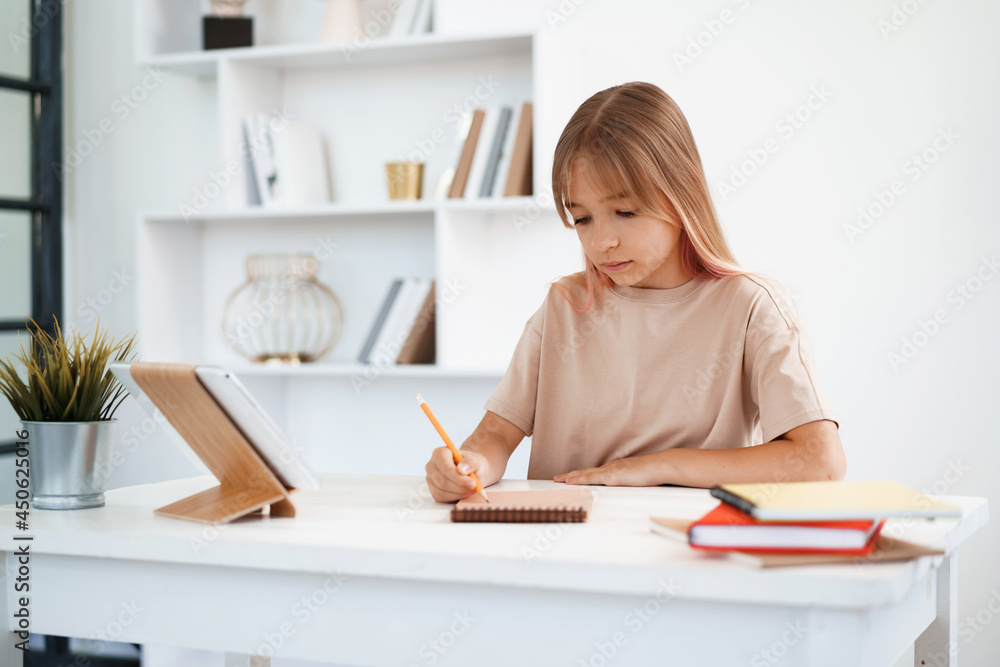 Teenage girl making notes in notepad, doing homework at table at home Teenage girl making notes in notepad, doing homework at table at home