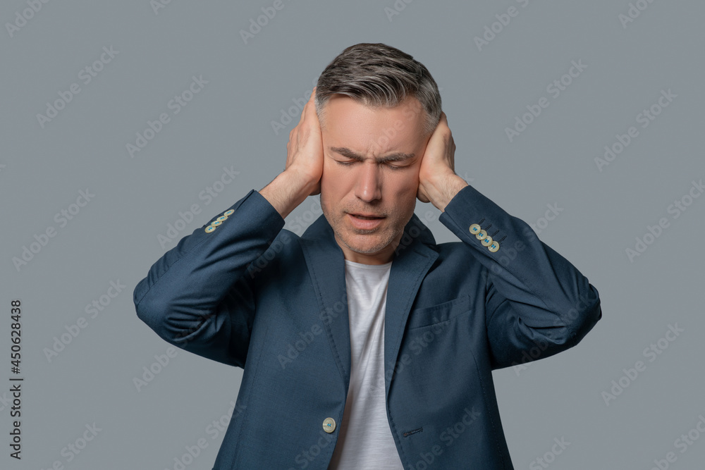 Man with drooping eyelids covering ears with hands Man with drooping eyelids covering ears with hands