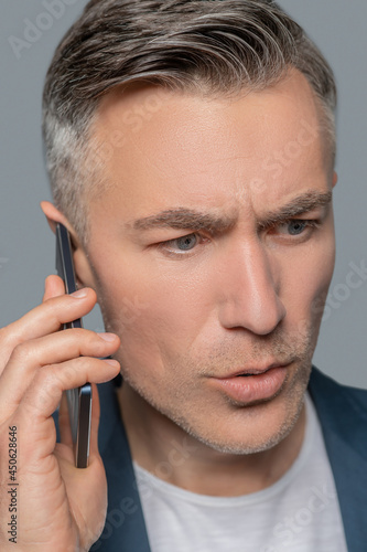 Serious alarmed man with smartphone near ear