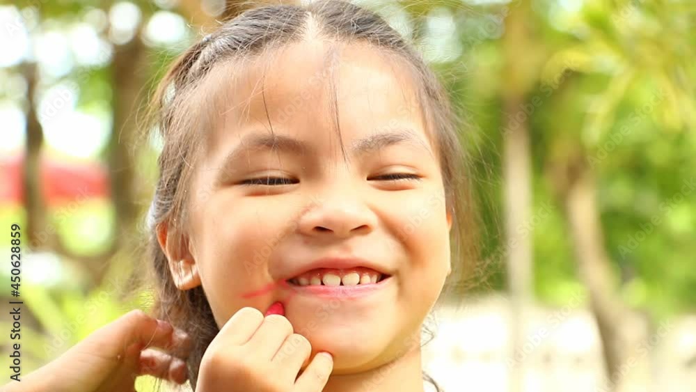 Thai child putting on make up his sister face, out door Chiangmai Thailand. Thai child putting on make up his sister face, out door Chiangmai Thailand.