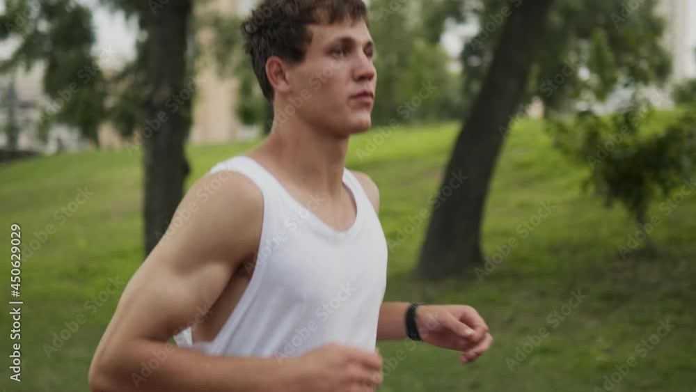 A handsome guy is running at playground outdoors while using his fitness tracker A handsome guy is running at playground outdoors while using his fitness tracker