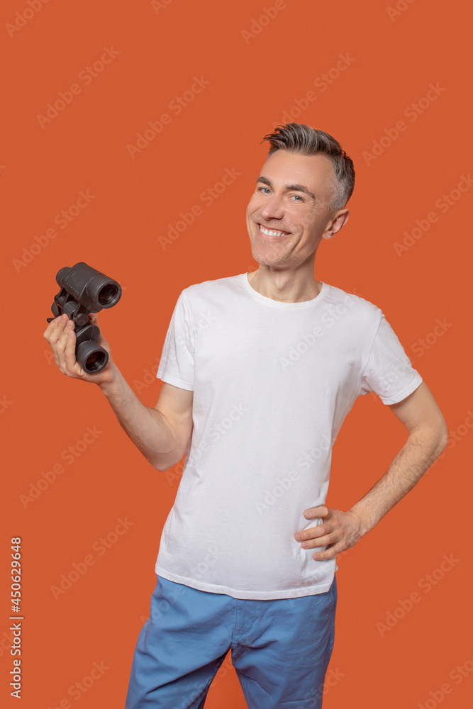 Young adult smiling man standing with binoculars Young adult smiling man standing with binoculars