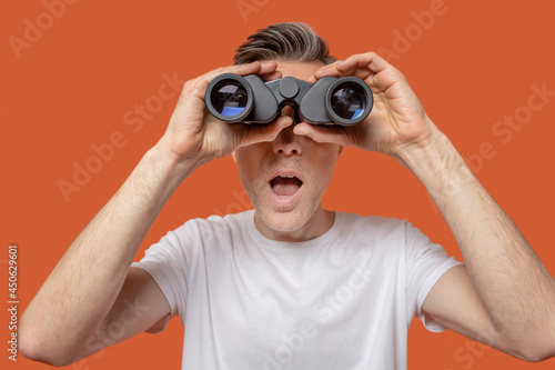 Man looking through binoculars with open mouth