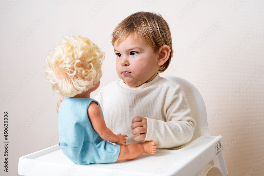 Baby toddler plays with old-fashioned doll on a studio shot. Funny ...