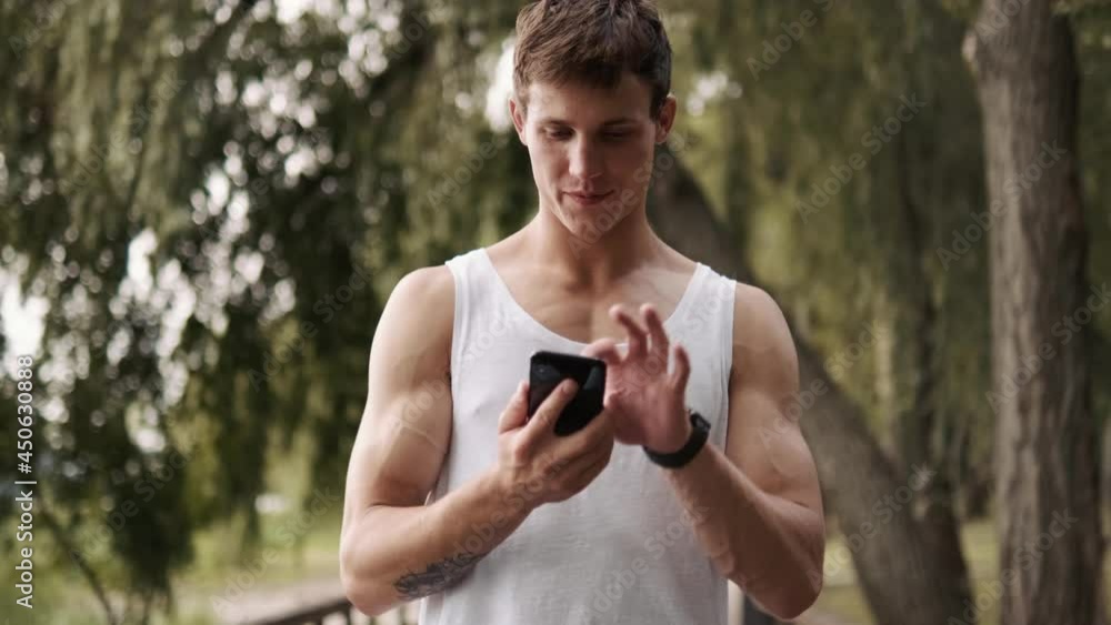 A handsome guy is turning off his mobile walking in the park outside A handsome guy is turning off his mobile walking in the park outside