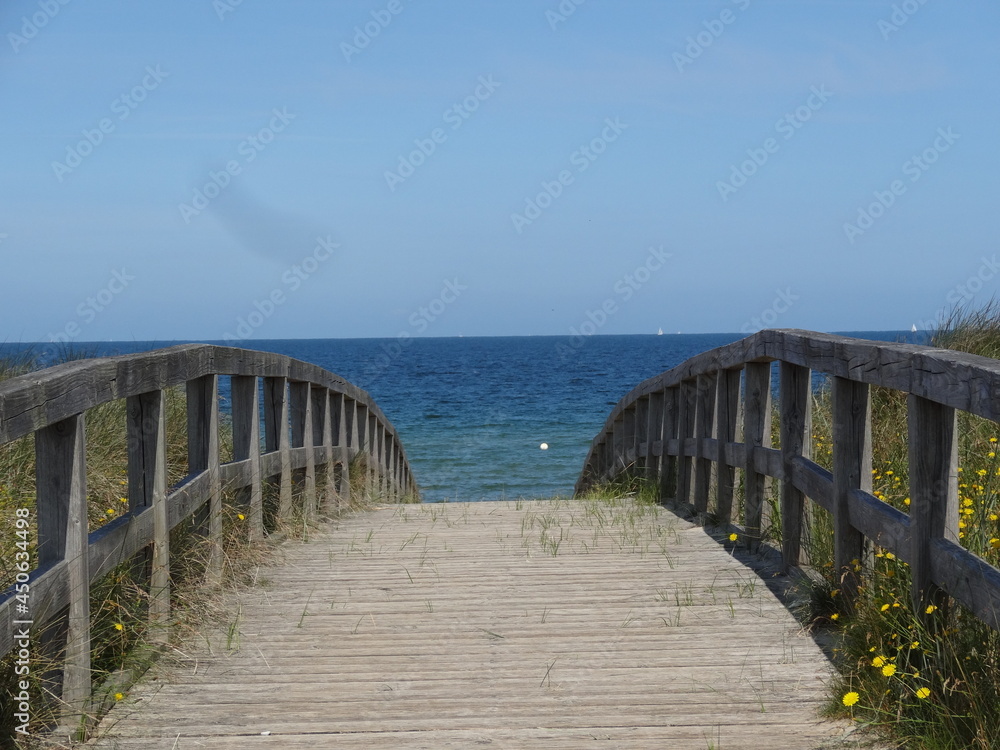 Holzbrücke auf dem Weg zum Meer mit blauem Himmel