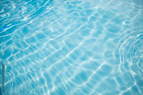 Surface of blue swimming pool. Summer water sport, recreational background. Texture of water surface, blue turquoise vivid bright sunny day closeup.