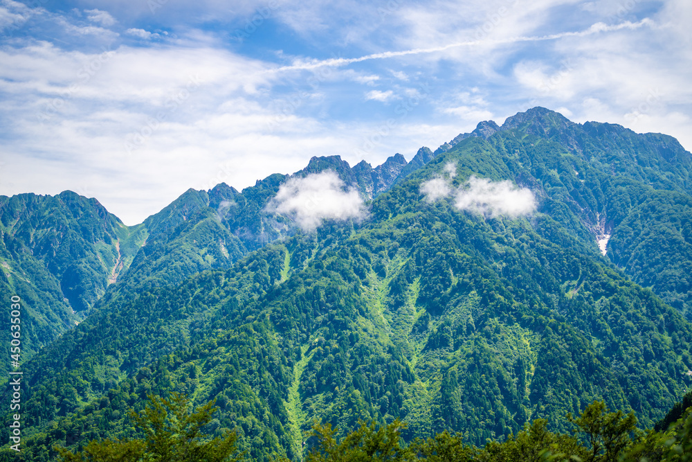 Fototapeta premium 富山県中新川郡上市町の中山から立山の剱岳を望む登山をしている風景 A view of mountain climbing with a view of Tsurugidake in Tateyama from Nakayama in Kamiichi Town, Nakashinagawa County, Toyama Prefecture.