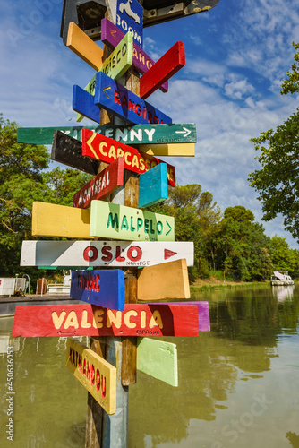 Photography Signpost with signs indicating the direction of various cities in the world with different colors on the Canal du Midi