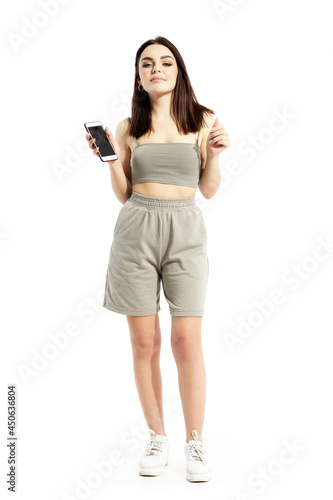 Young pretty gen Z woman listening to music on smart phone app dancing. Full body portrait isolated on white background