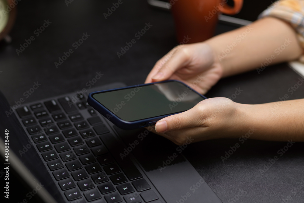 female hands holding mobile phone with tablet keyboard on black working desk female hands holding mobile phone with tablet keyboard on black working desk