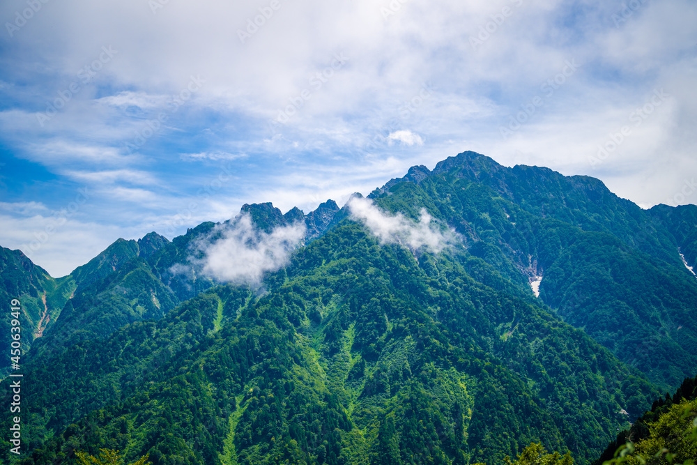 Obraz premium 富山県中新川郡上市町の中山から立山の剱岳を望む登山をしている風景 A view of mountain climbing with a view of Tsurugidake in Tateyama from Nakayama in Kamiichi Town, Nakashinagawa County, Toyama Prefecture.
