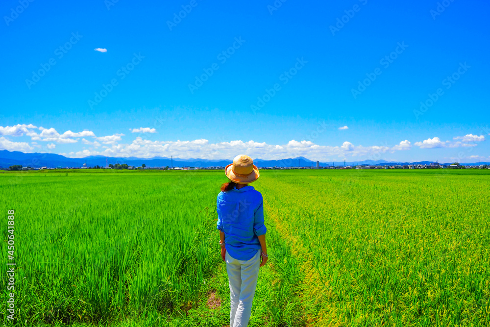 麦わら帽子を被っている女性と田園風景