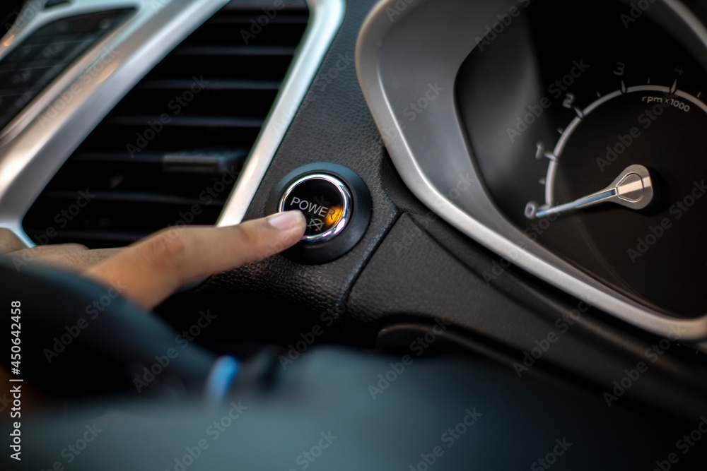person driving a car, pressing the start button