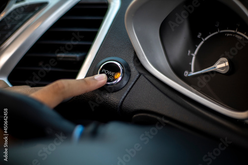 person driving a car, pressing the start button © Andri