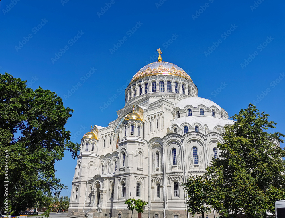 St. Nicholas Cathedral among the trees against the background of a cloudless sky, on a summer day in Kronstadt.