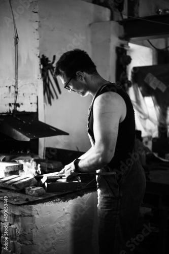 The blacksmith in the production process of metal products handmade in the forge. Black and white photo