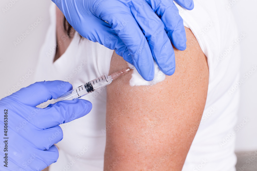 Female doctor or nurse giving shot or vaccine to patient's shoulder. Close-up. Vaccination against flu, pandemic coronavirus. Mandatory prevention of people for immunity from the virus. Female doctor or nurse giving shot or vaccine to patient's shoulder. Close-up. Vaccination against flu, pandemic coronavirus. Mandatory prevention of people for immunity from the virus.