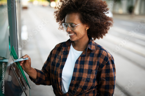 Beautiful African girl using ATM machine. Happy smiling young woman withdrawing money from credit card.