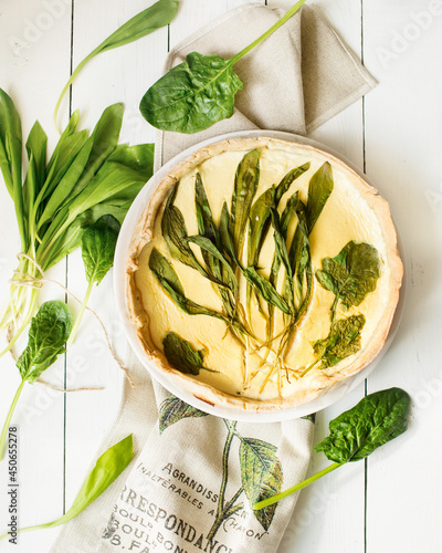 French cuisine. Quiche with spinach and wild leeks. Green food. French pastries on a white table. wild garlic.