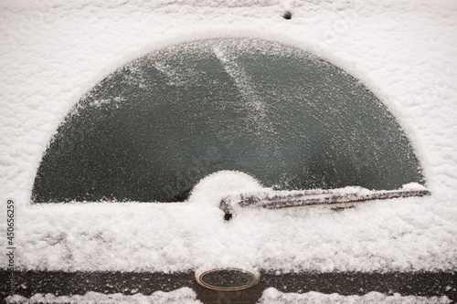 Car wiper blade remove snow from car window. Snow flakes covered the car in a thick layer. Preparing for the trip in a winter, snowy day on the icy car. Safe winter driving. Selective focus