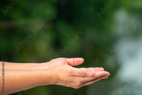 Man Hand over blur nature background, Hand holding object with fingers over blur nature background with empty space. © MERCURY studio