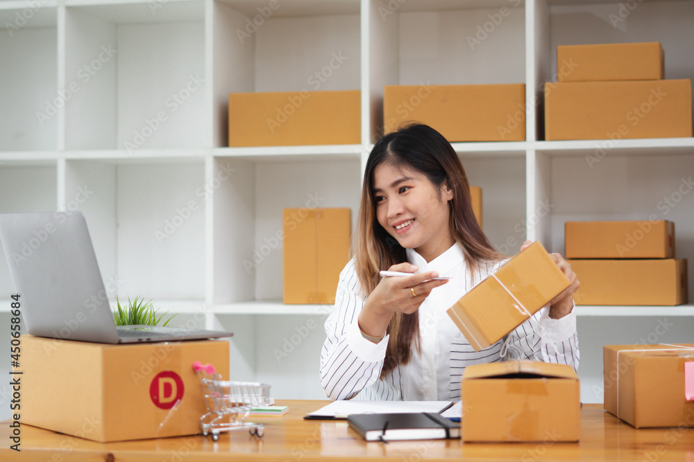 Startup small business entrepreneur SME, young asian woman working with laptop computer and delivery packaging box, online market packing, SME e-commerce seller concept. Startup small business entrepreneur SME, young asian woman working with laptop computer and delivery packaging box, online market packing, SME e-commerce seller concept.