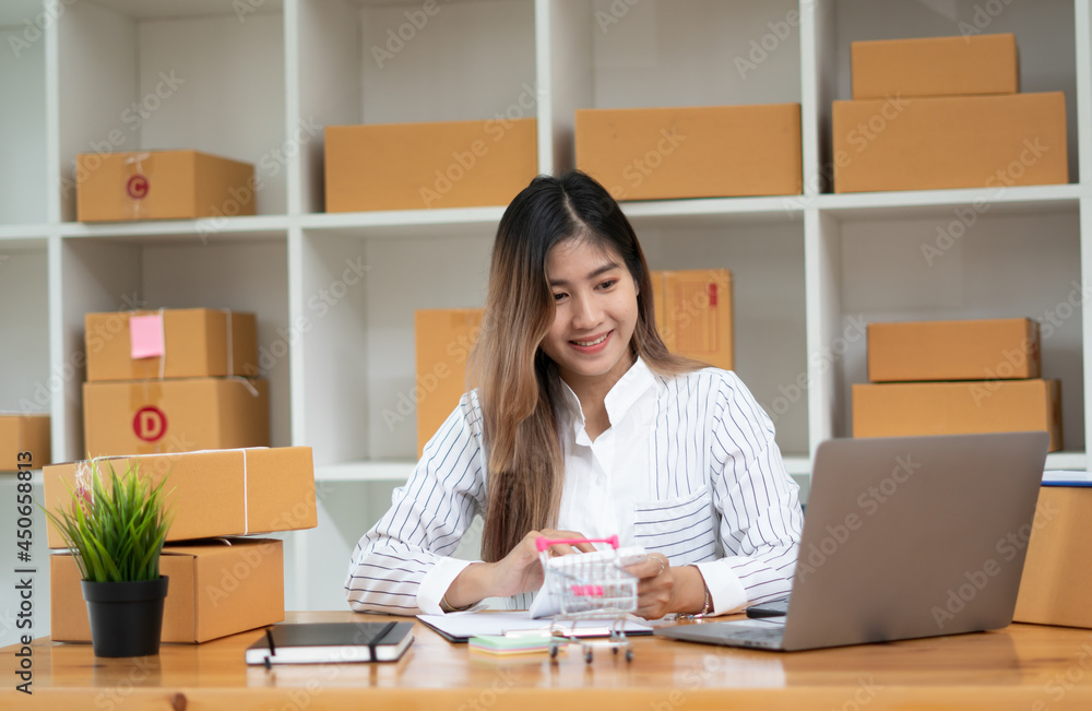Startup small business entrepreneur SME, young asian woman working with laptop computer and delivery packaging box, online market packing, SME e-commerce seller concept. Startup small business entrepreneur SME, young asian woman working with laptop computer and delivery packaging box, online market packing, SME e-commerce seller concept.