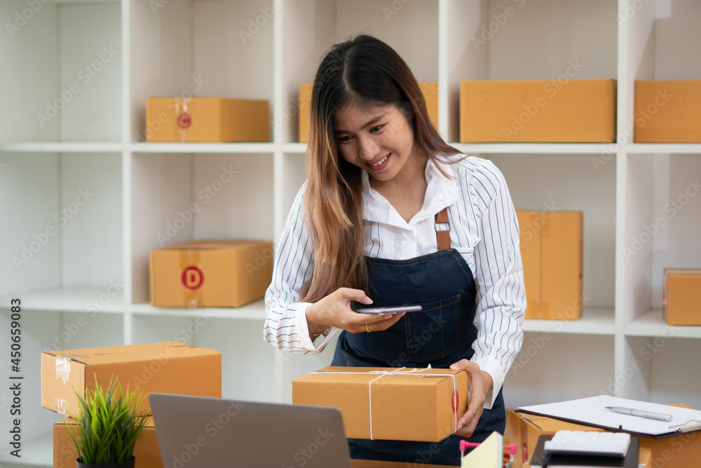 Startup small business entrepreneur SME, young asian woman working with laptop computer and delivery packaging box, online market packing, SME e-commerce seller concept. Startup small business entrepreneur SME, young asian woman working with laptop computer and delivery packaging box, online market packing, SME e-commerce seller concept.