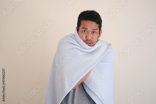 Adult Asian man feeling cold and cover his body using blanket photo