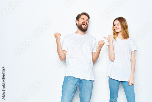 cheerful young couple in white t-shirts and jeans studio posing light background