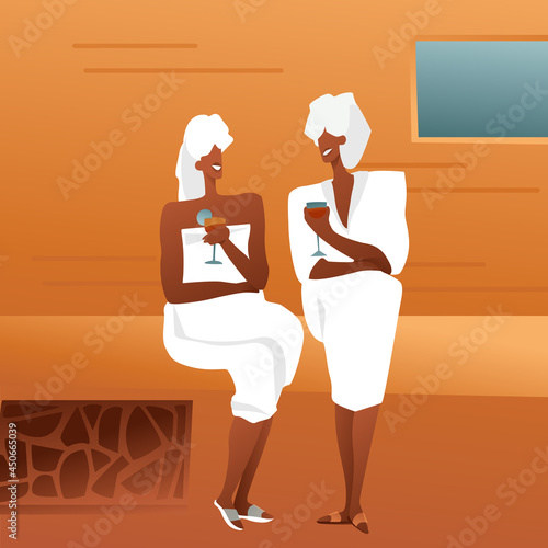 Adult ladies in a bathhouse in white coats with towels and drinks in glasses are sitting on a tree and talking. Girls gossip in the sauna, the concept of relaxing with friends.