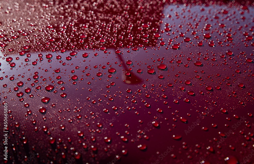 Hydrophobic water effect on red car paint after rain. Water drops on metal surface